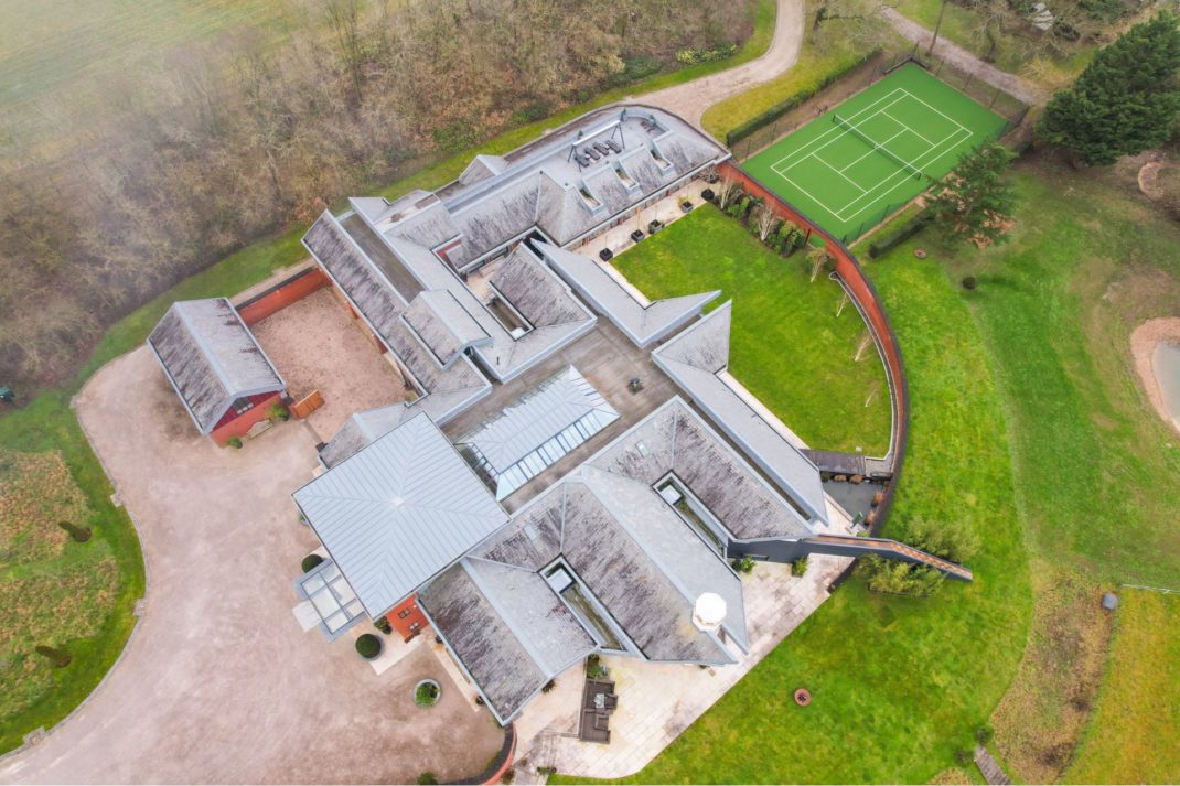 Aerial view of country manor with lawn and tennis court