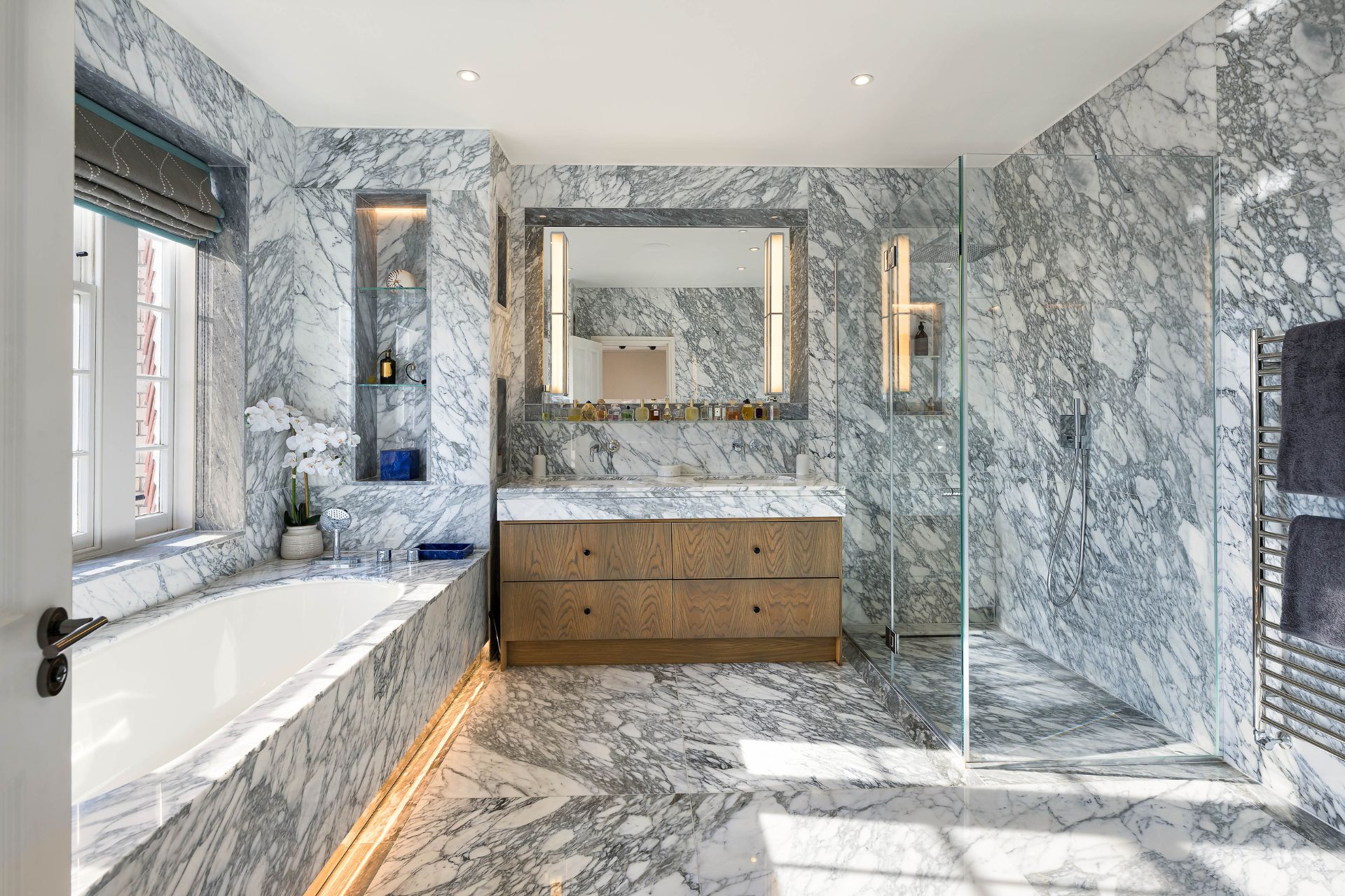 Grey and white marble bathroom with a built-in bathtub and an oak sink vanity
