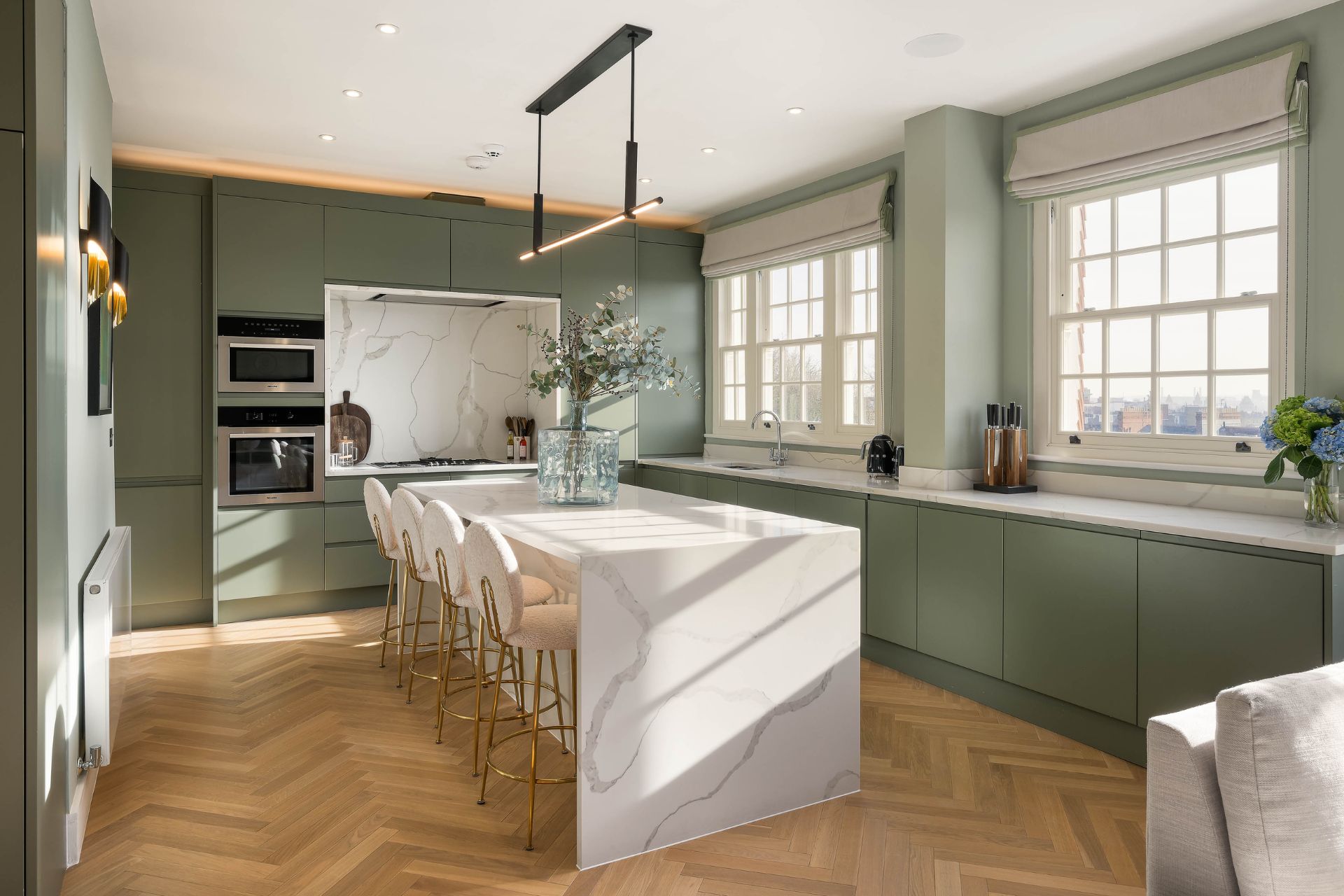 Kitchen with sage green cabinets, white wokrktops and a white marble island