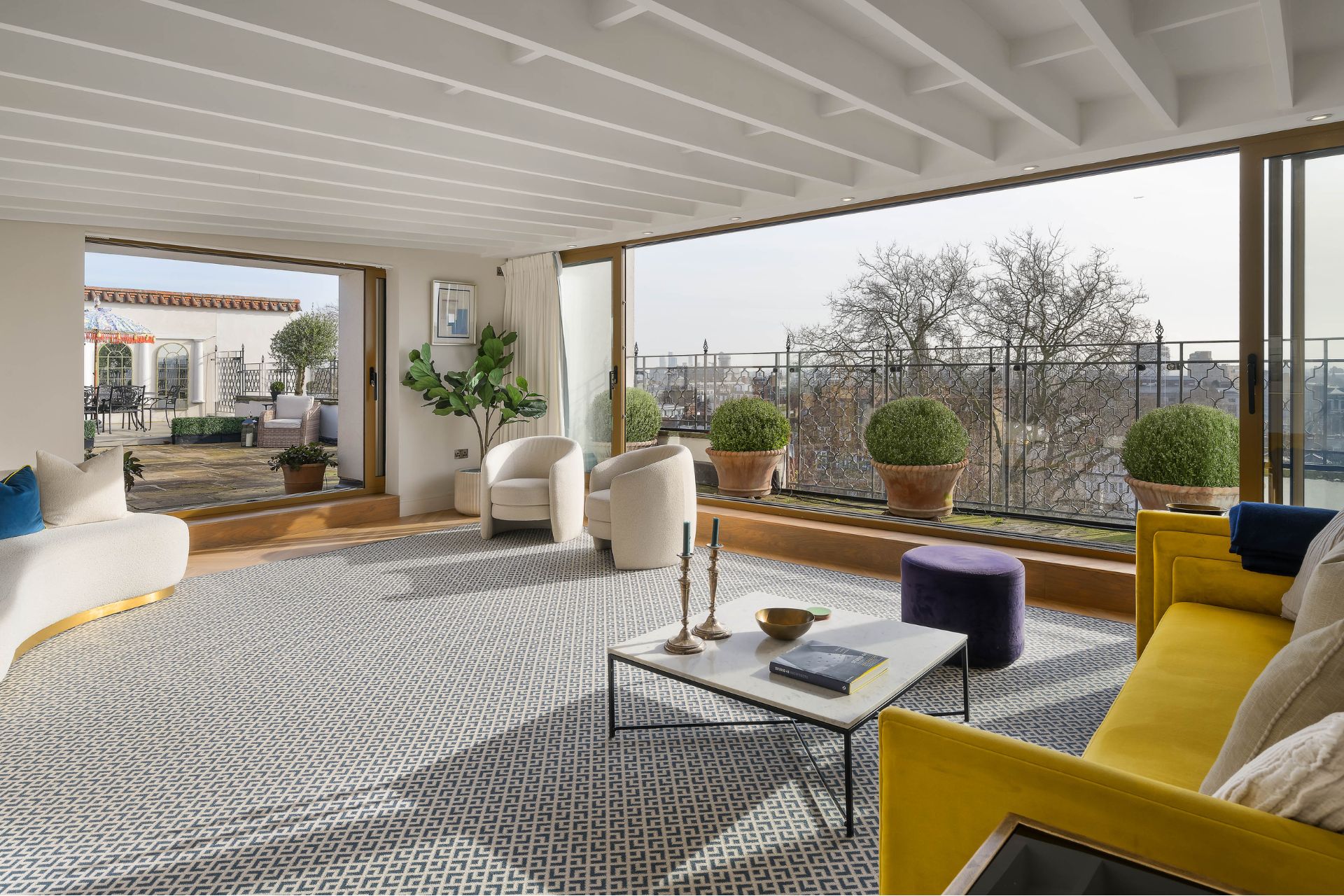 Living room with a grey rug, cream sofas and floor-to-ceiling windows