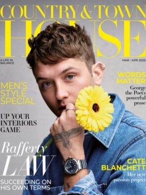 Rafferty Law wears a denim shirt and holds a yellow flower