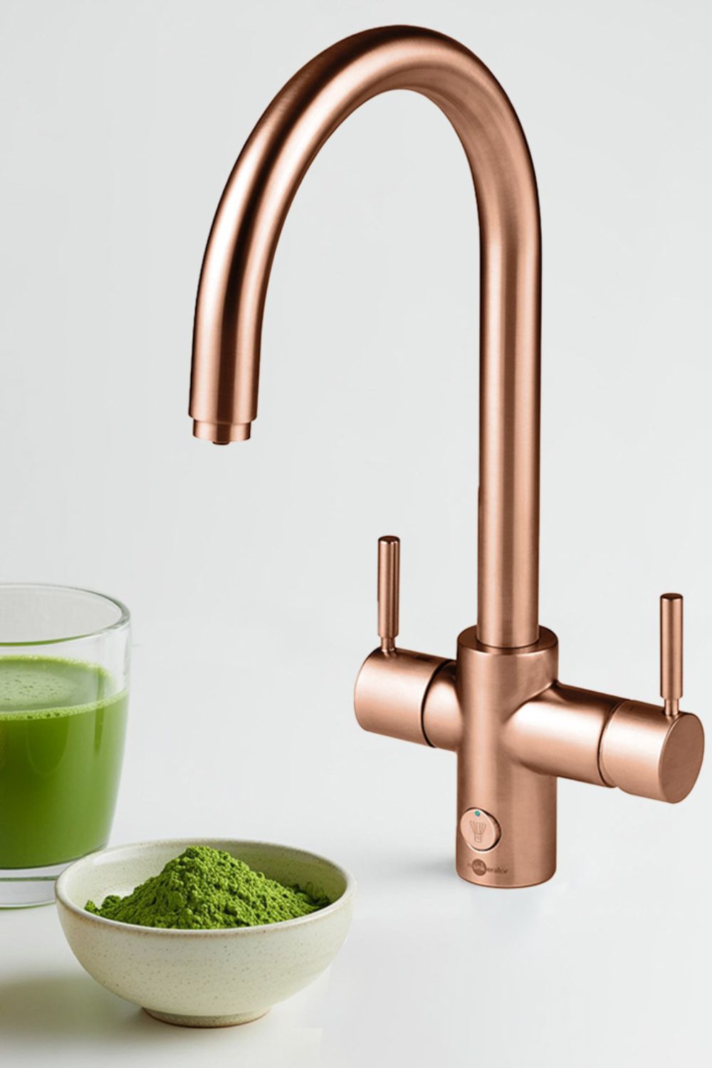 Rose gold tap with a mug of matcha and a bowl of matcha powder beside it