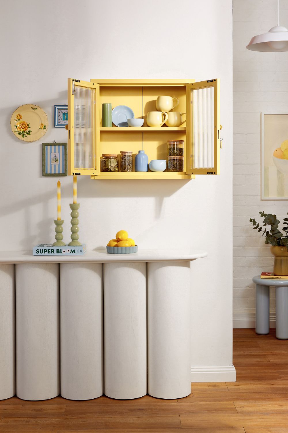 Living room with scalloped white sideboard and yellow glass-front cabinet