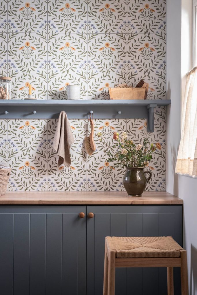 Utility room with floral tiles and dusky blue cabinets with wooden worktops