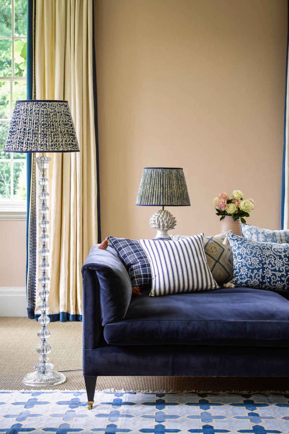 Taupe living room with navy velvet sofa, two blue and white patterned lamps, and a blue and white patterned rug