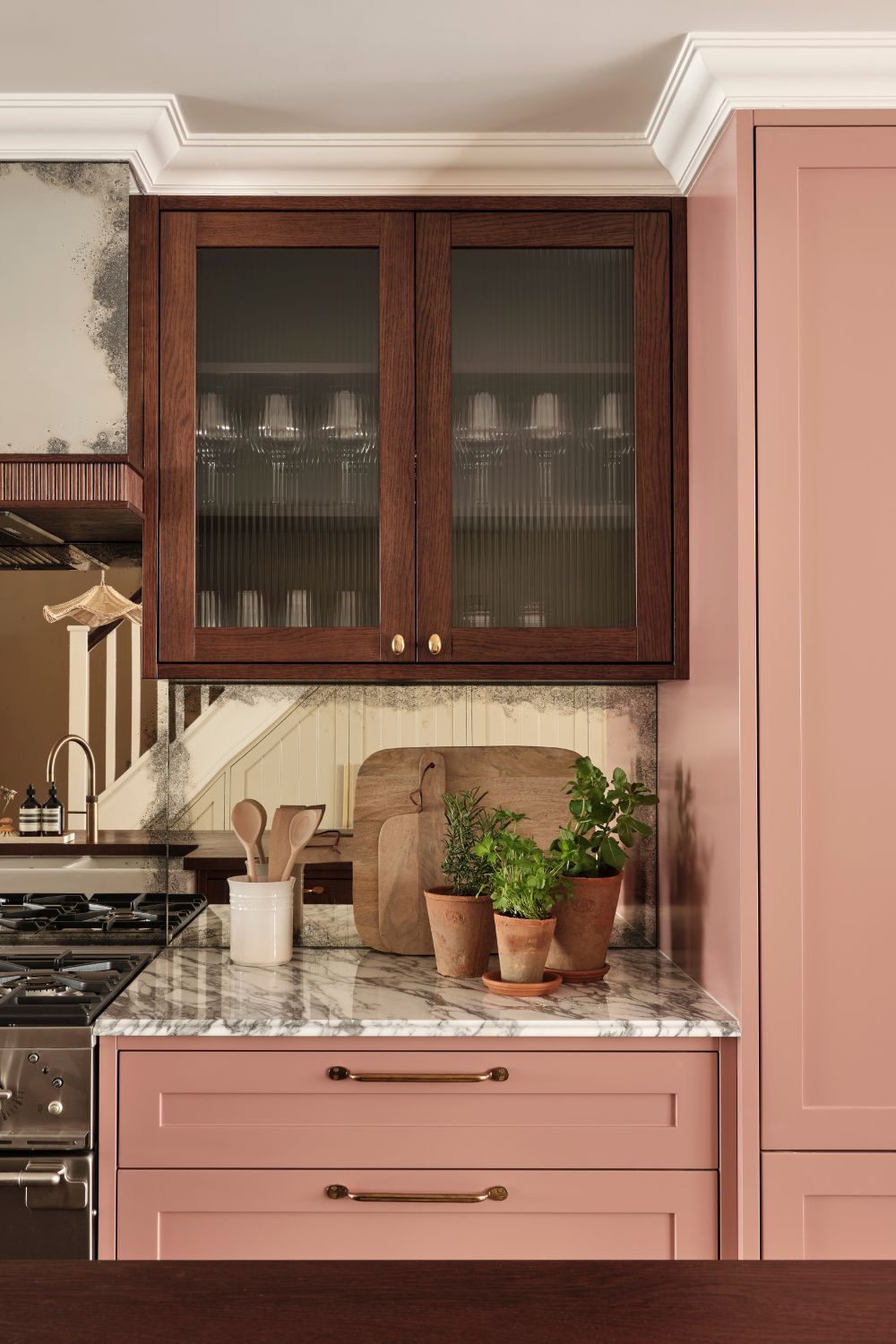 Kitchen with raspberry pink cabinets, dark wooden upper cupboards and white marble worktops