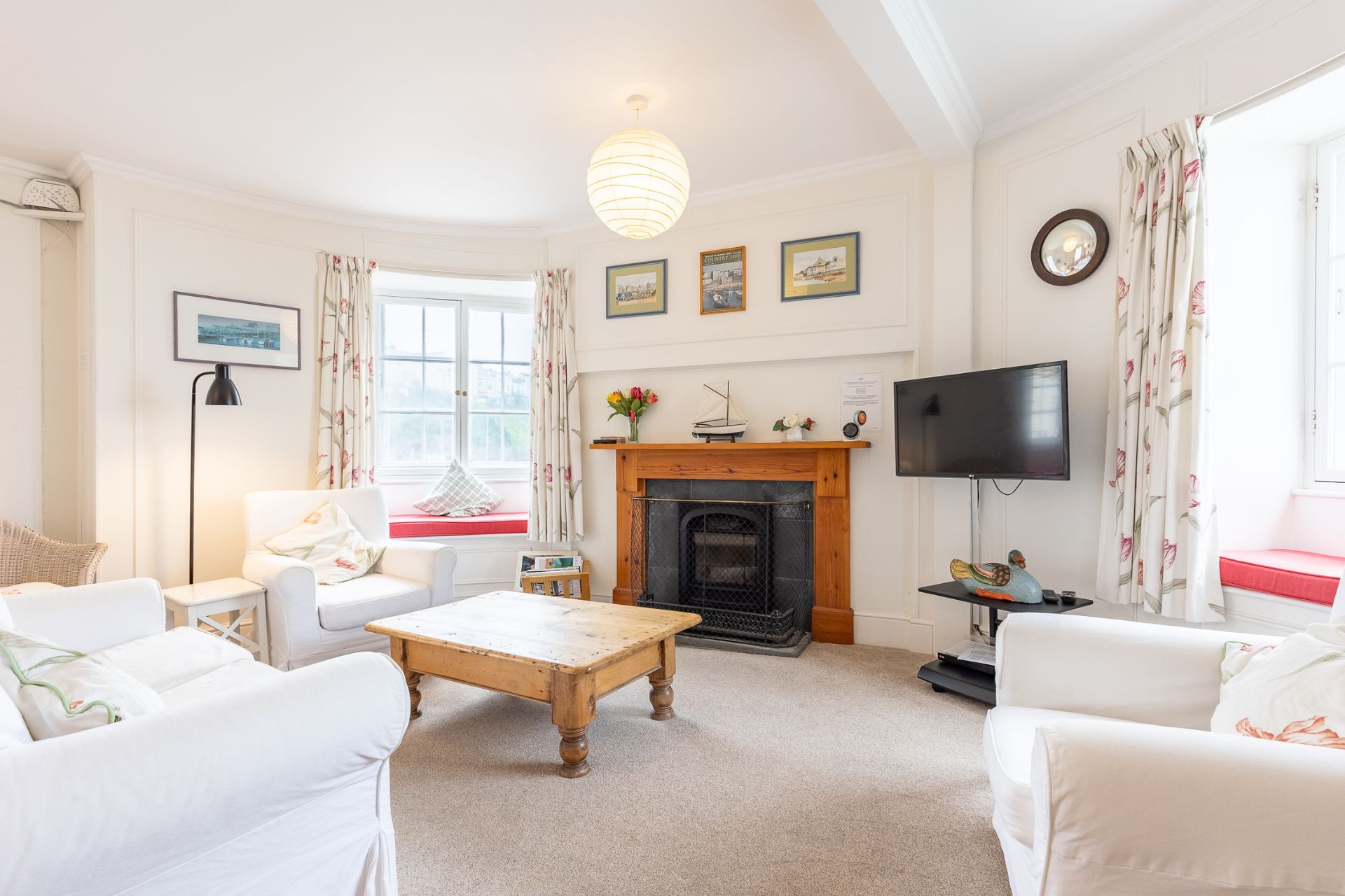 Living room with white sofas, a wooden coffee table and a period fireplace