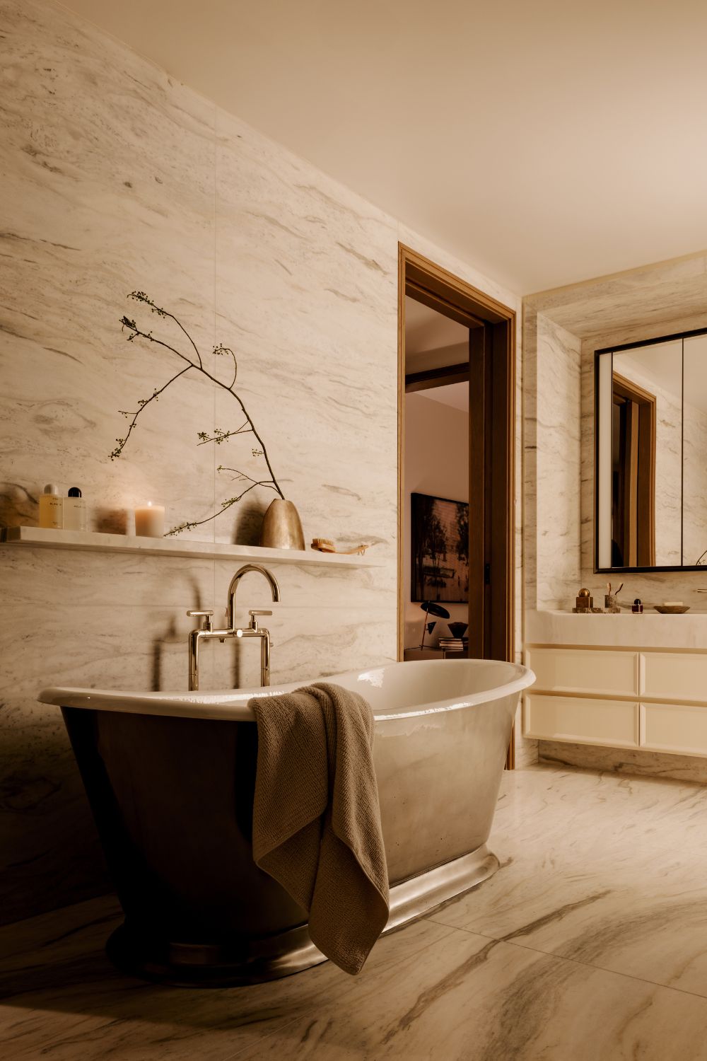 Bathroom with veined white marble walls and a grey standalone bathtub