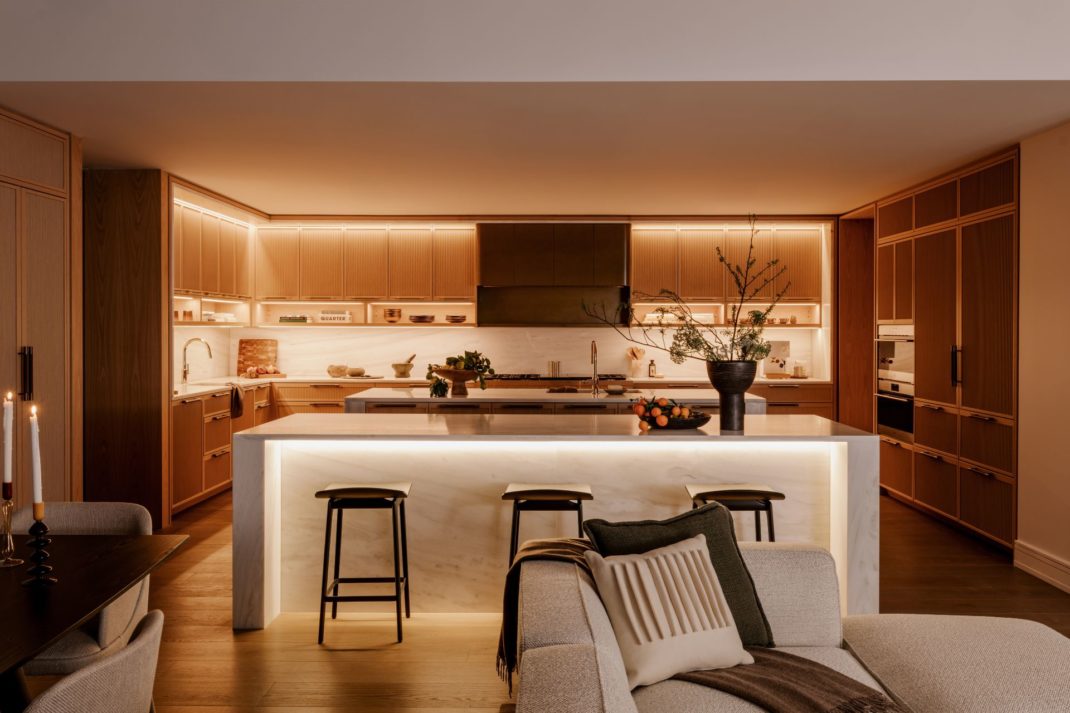 Sleek modern kitchen wirh white worktops, a white marble island and black barstools