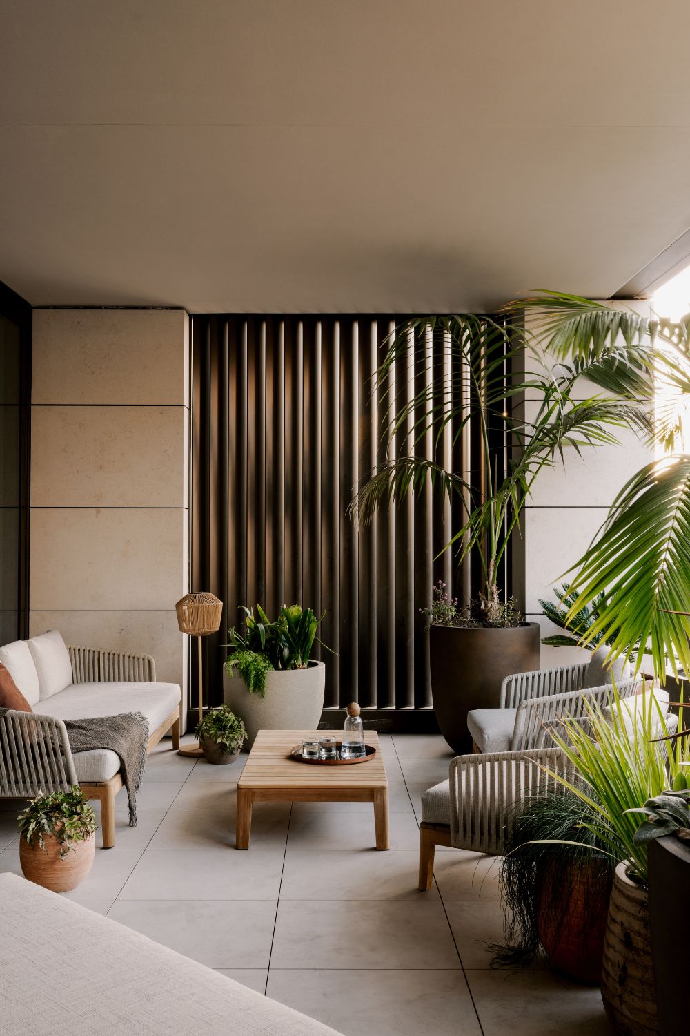 Apartment terrace with white outdoor furniture, wood panelling and large plants