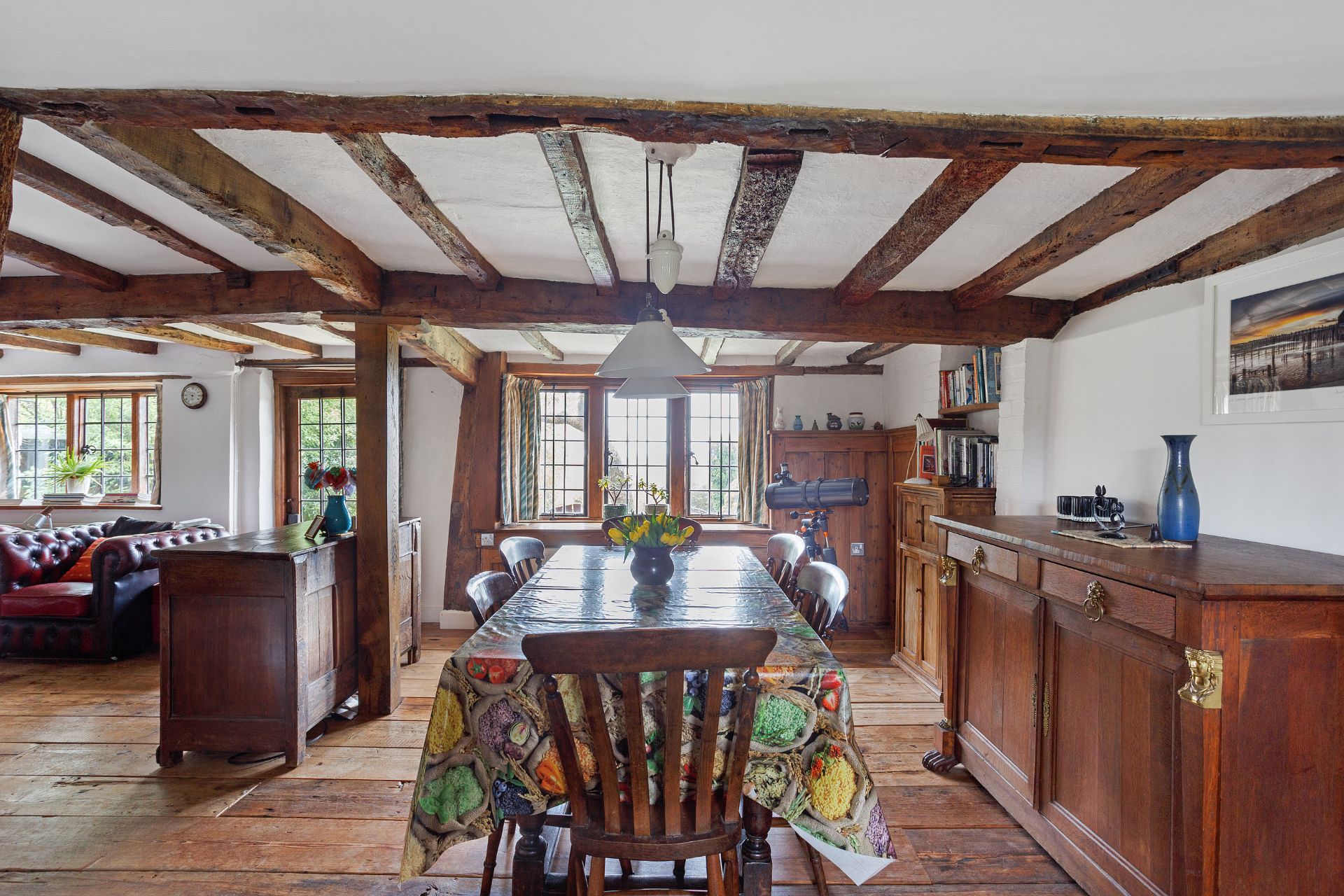 Dining room with wooden furniture, floral tablecloth, and wooden ceiling beams