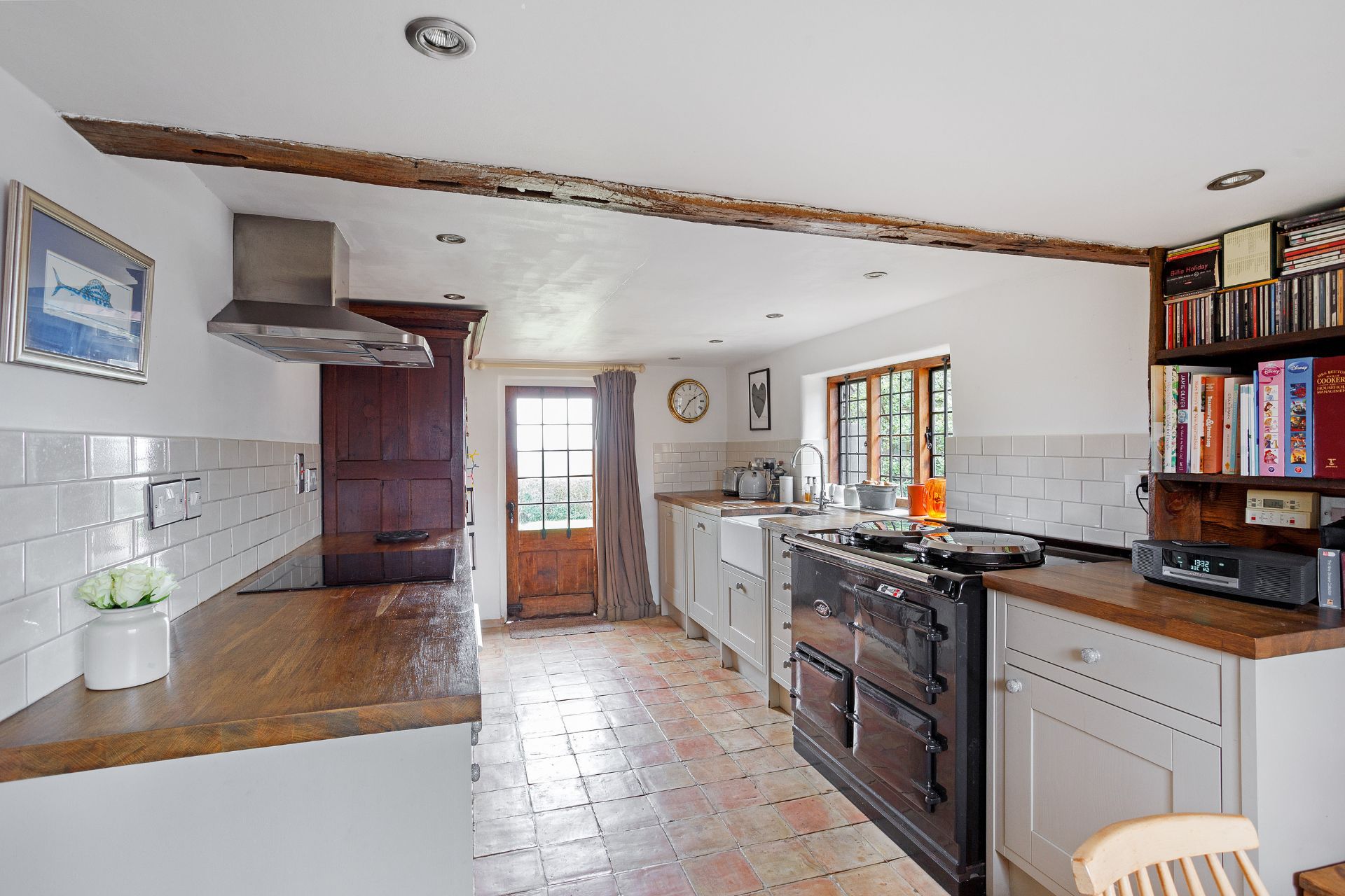 Kitchen with tiled floors, white cabinets, wooden worktops and an AGA