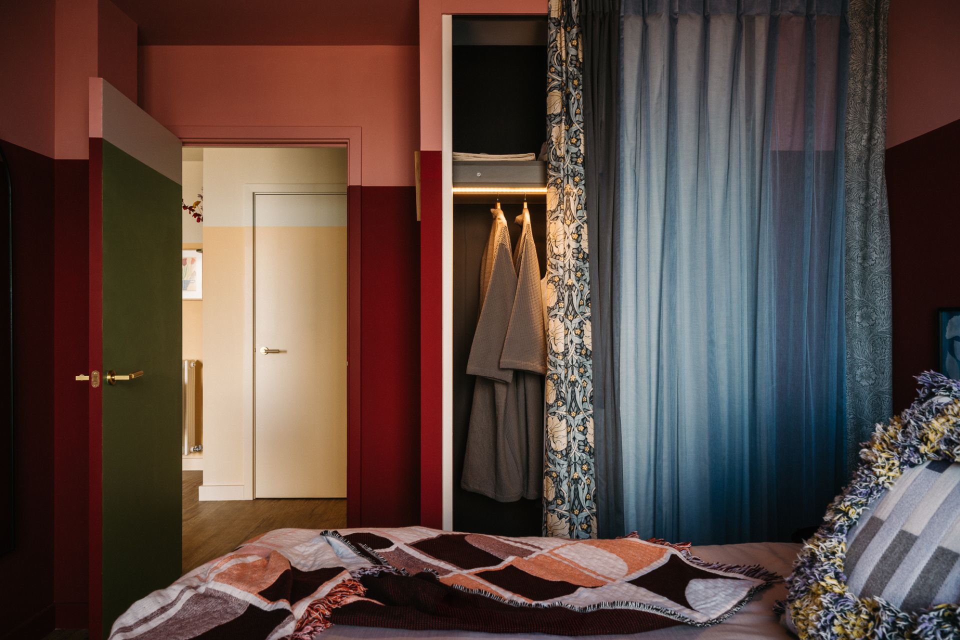 Bedroom with cherry red ealls, dusky blue curtains and white bedding