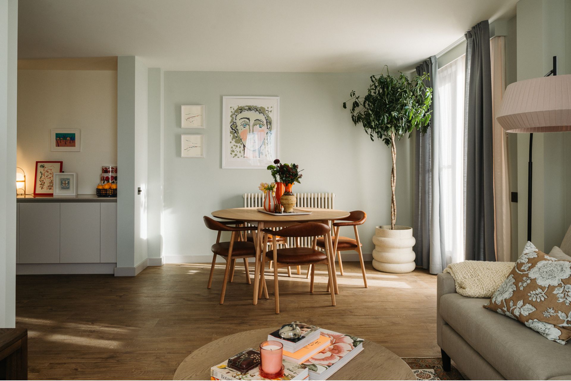 Living room with pale blue walls, circular wooden dining table and large potted plant