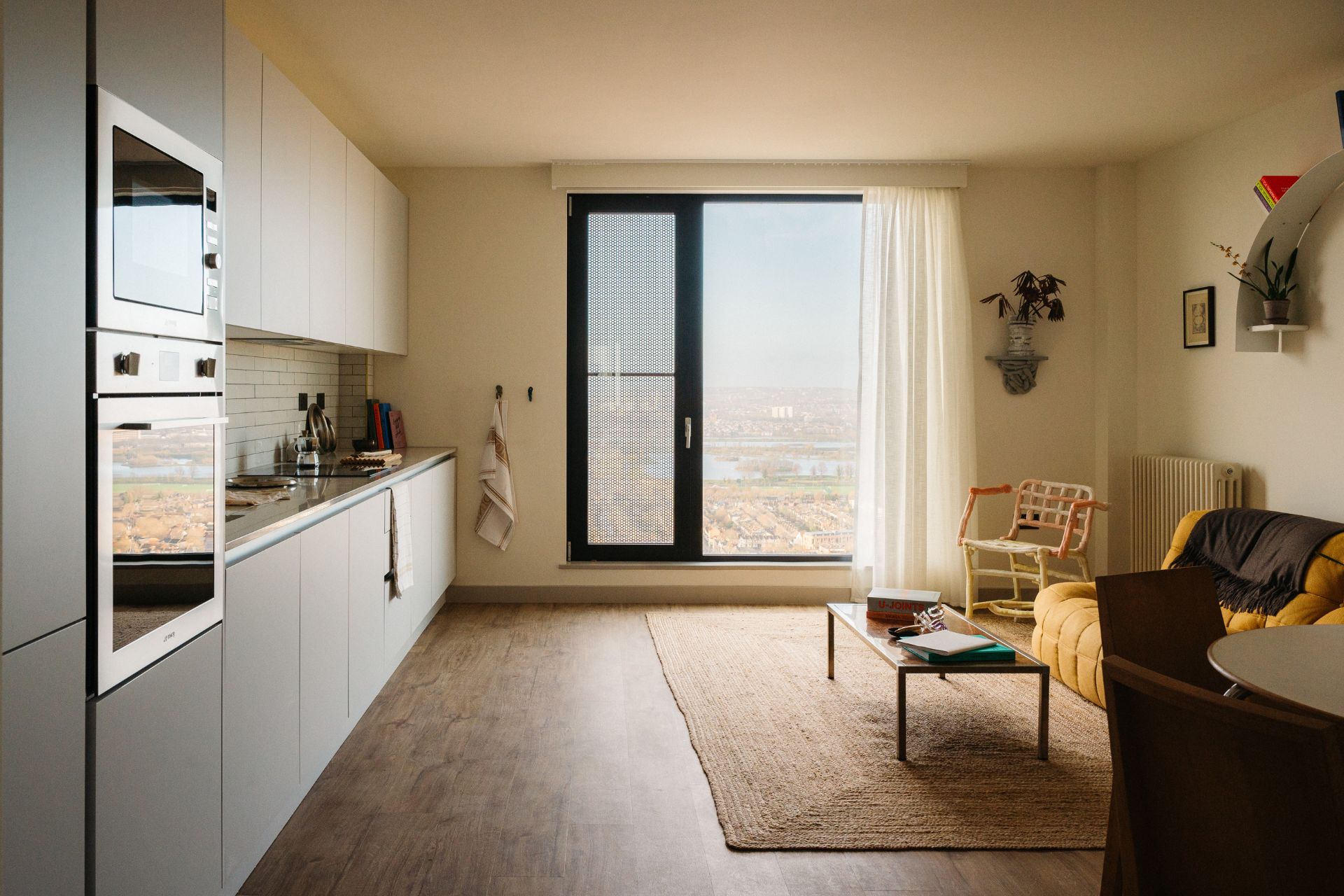 Modern kitchen with cream walls, white cabinets and floor-to-ceiling windows