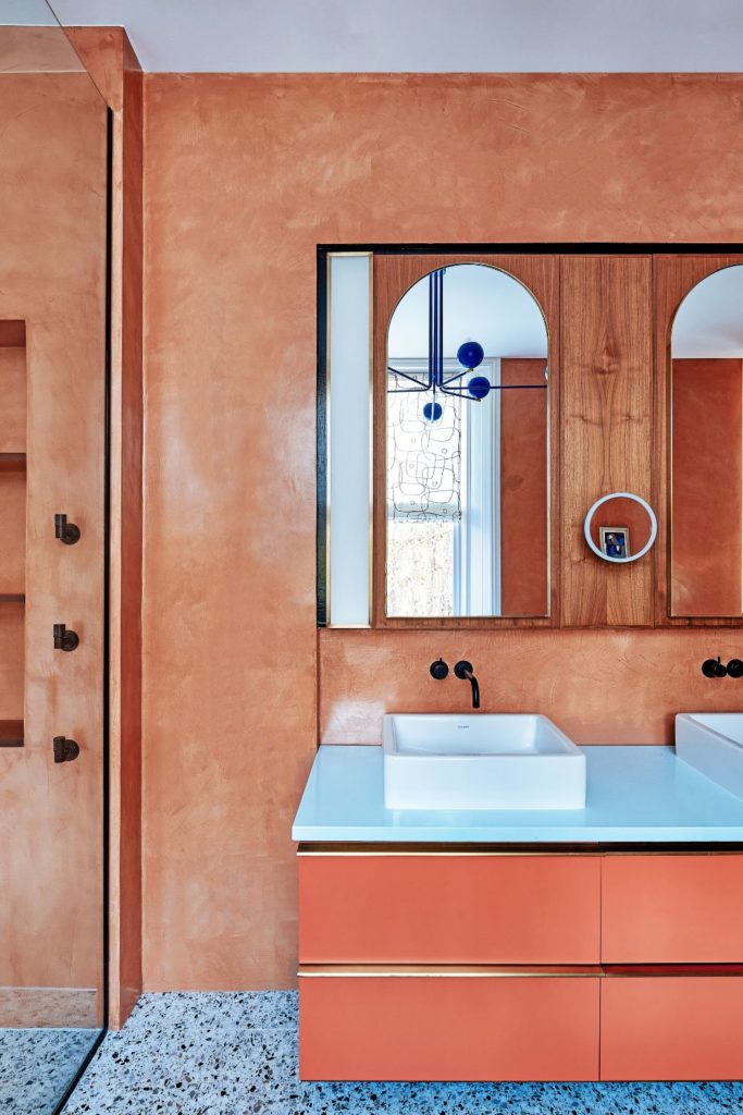 Bathroom with terracotta walls, matching vanity drawers, a blue tiled floor and a bright blue light fitting
