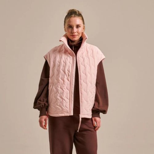 A woman wearing burgundy clothes with a pink oversized that she lay on top