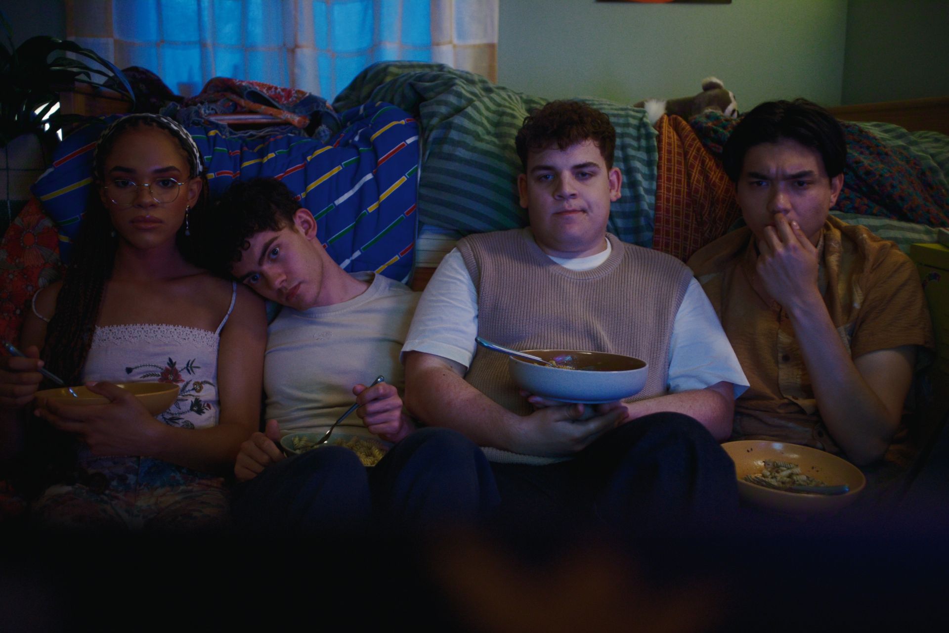 Four characters in Heartstopper Forever sitting on the floor watching a movie.