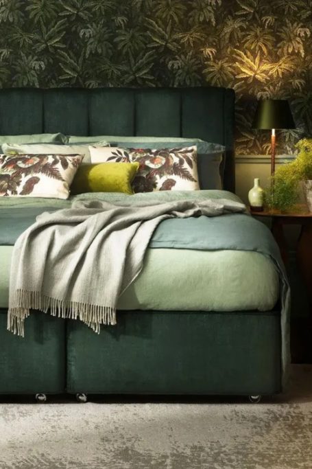 Green bed with matching bedding and wallpaper