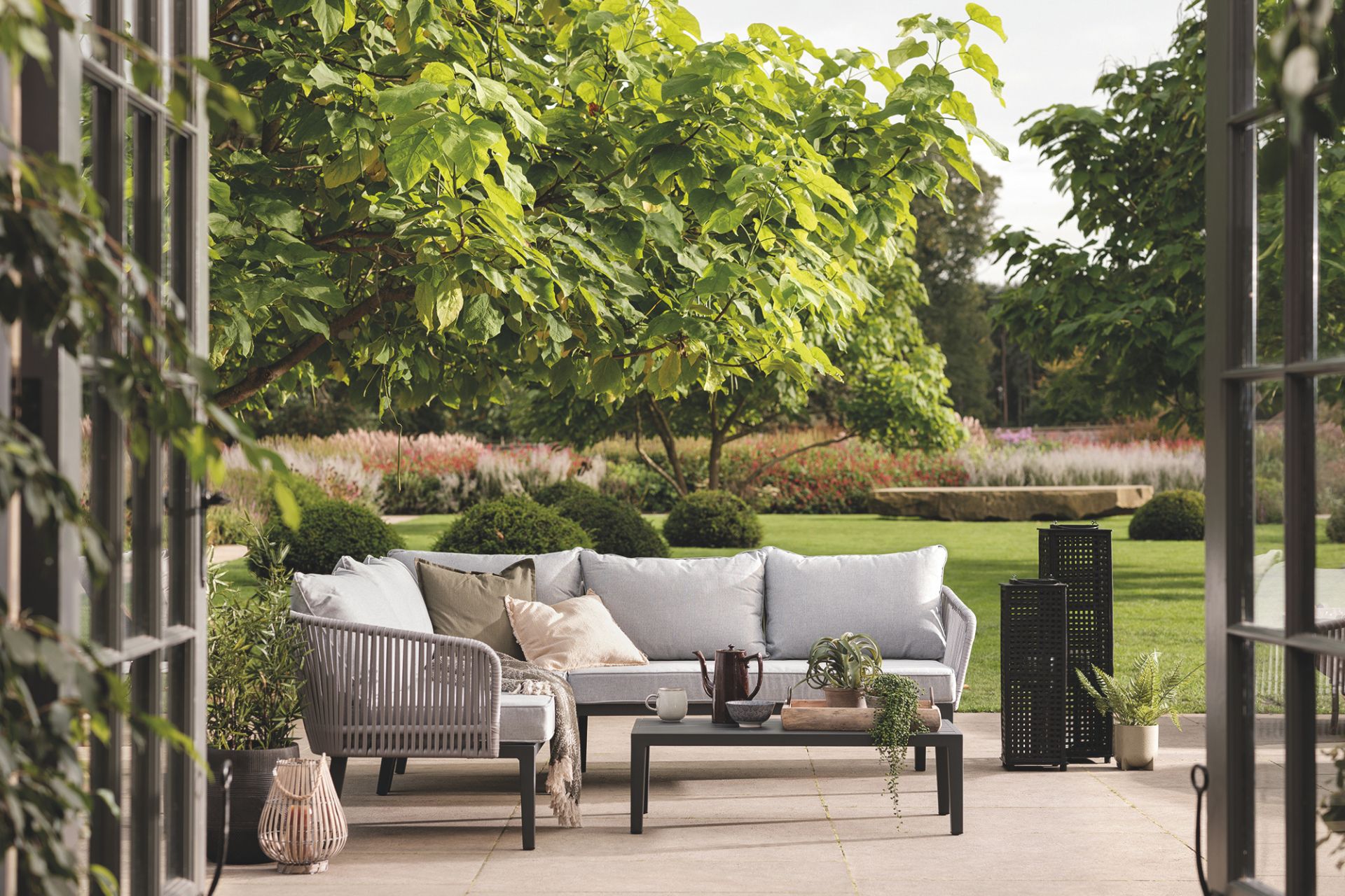 Large stone terrace with a pale grey outdoor sofa and low black table