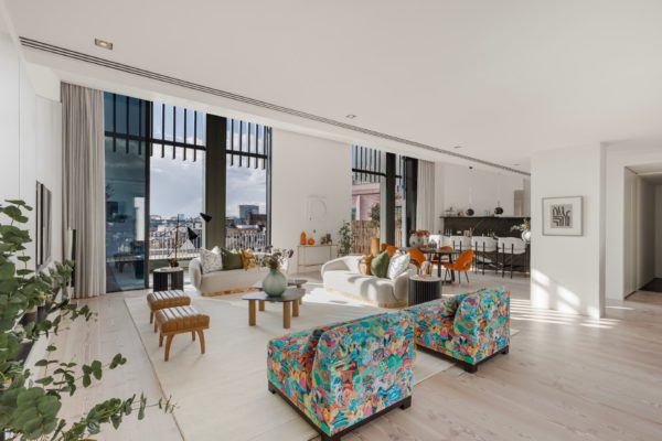 Penthouse living space with blue and yellow colour-splatter armchairs, boucle sofas and French doors