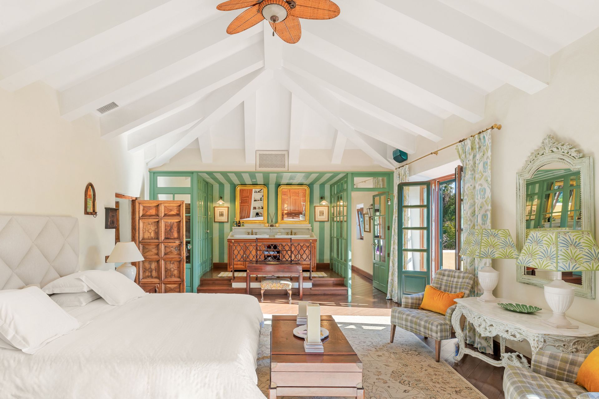 Bedroom with woodne floors, French doors, and a dressing area with green striped wallpaper