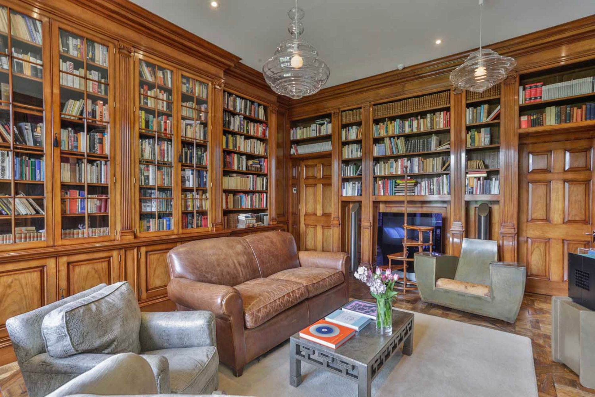 Wood-panelled living room with built-in bookcases and a brown leather sofa