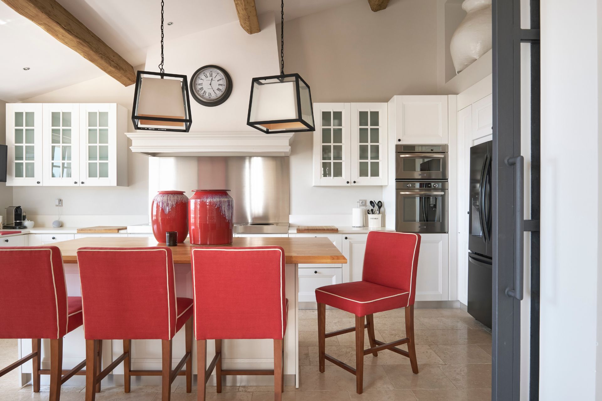 White Shaker kitchen with large island and red seats