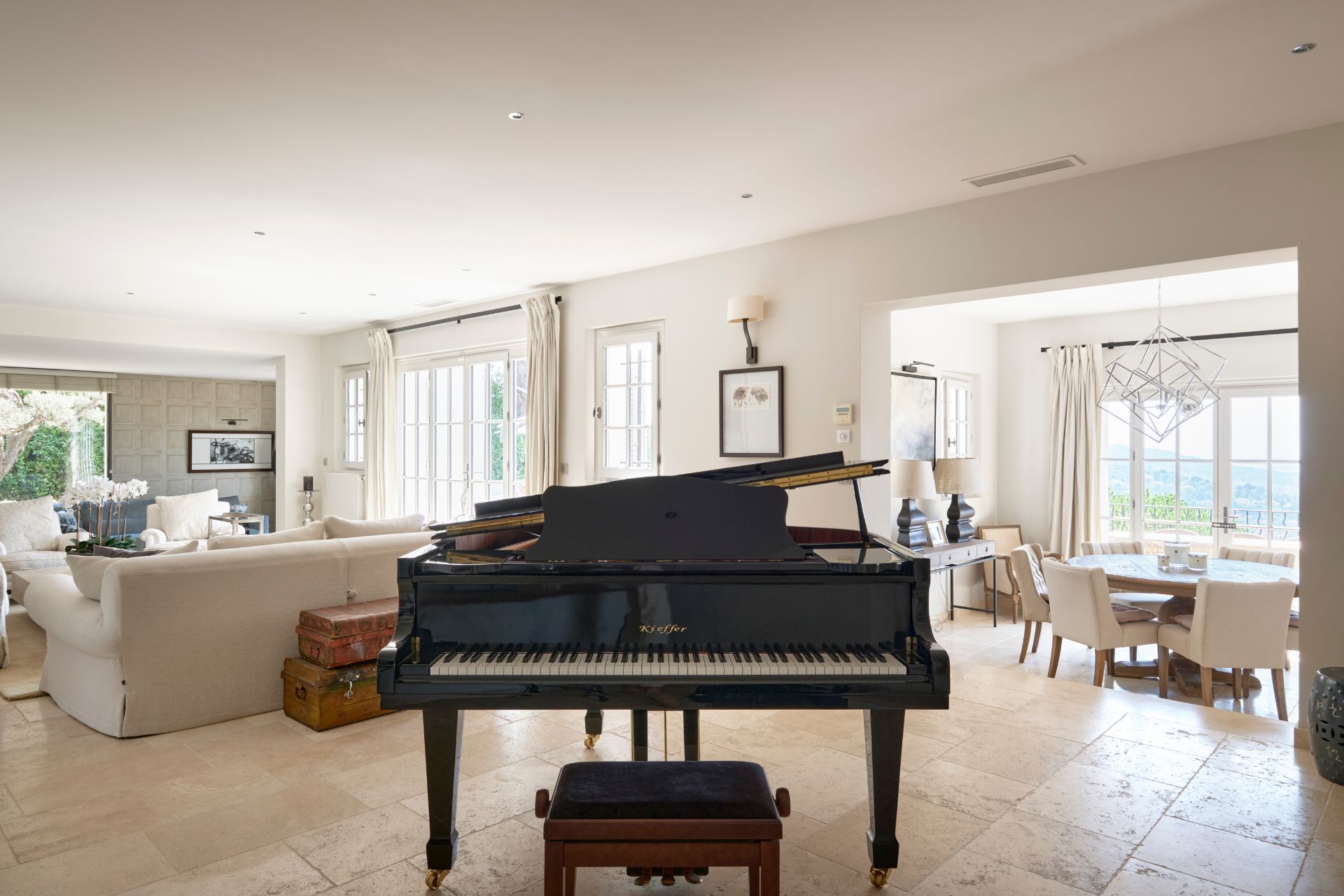 Villa living room with cream stone floors, cream sofas and a grand piano