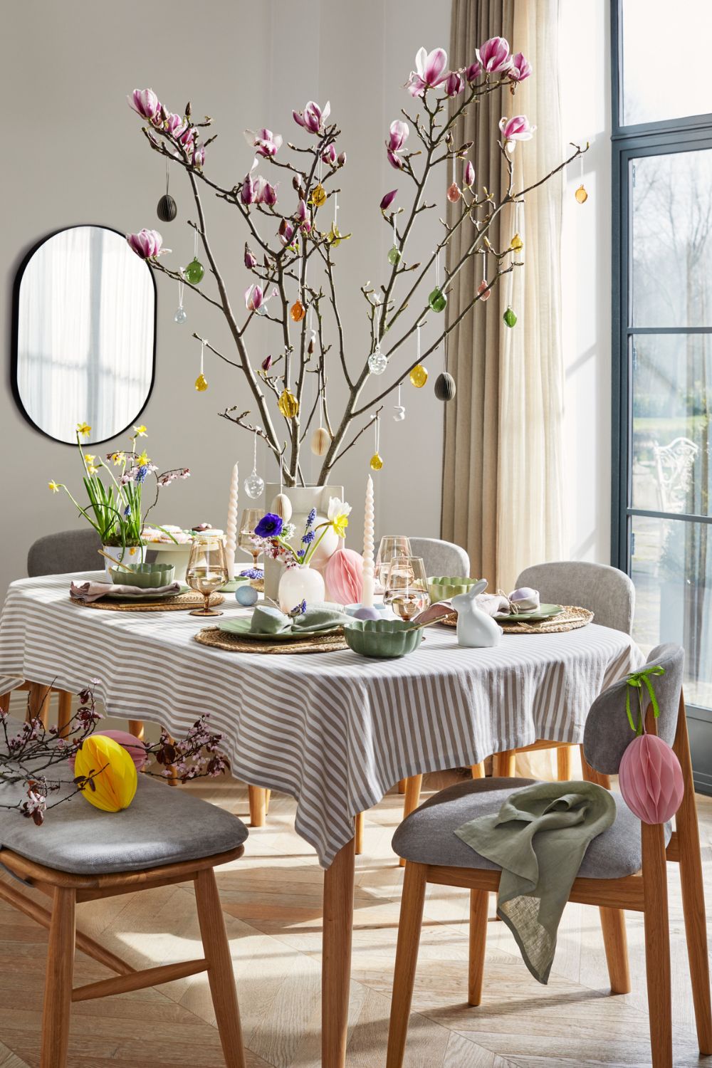 Pastel Easter table with magnolia branches hung with Easter egg decorations