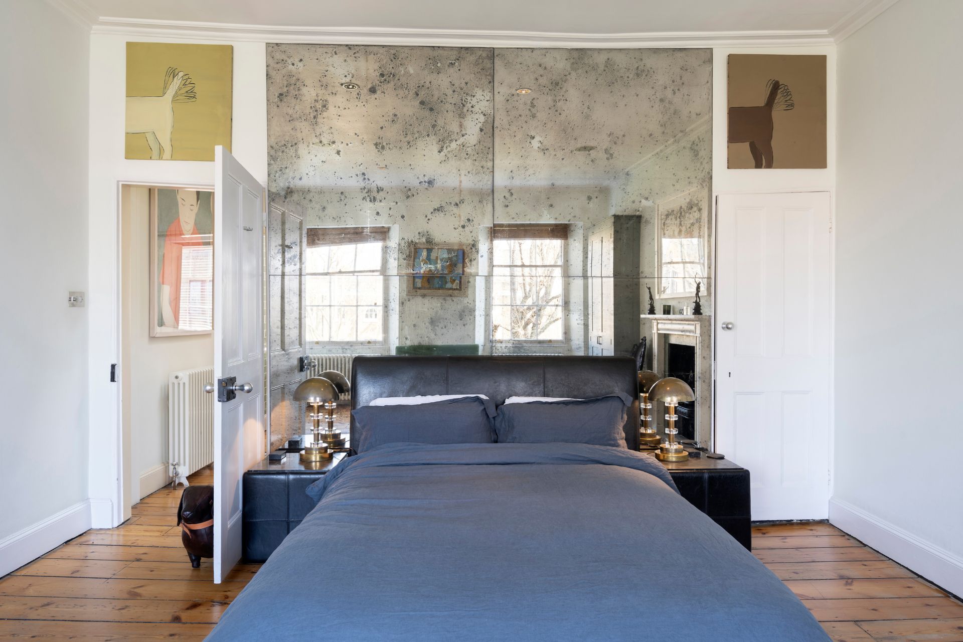 Bedroom with dusty blue bedding and floor-to-ceiling mirrored headboard