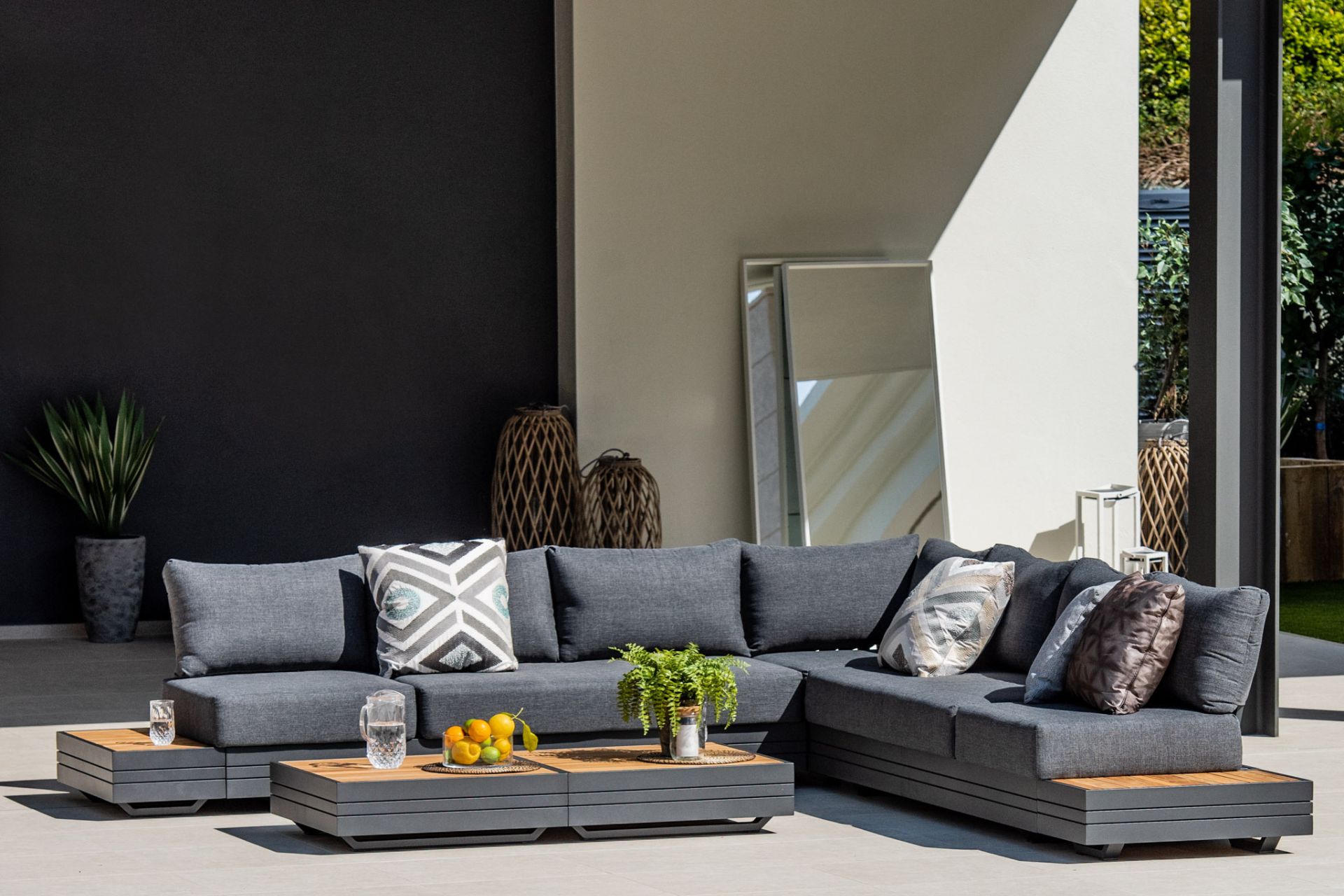 Dark grey L-shaped outdoor sofa with low wooden coffee table
