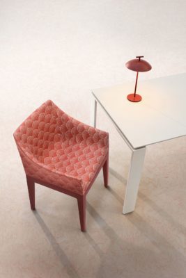 Red modern armchair in red Liberry print, with a white table and a wireless red lamp beside
