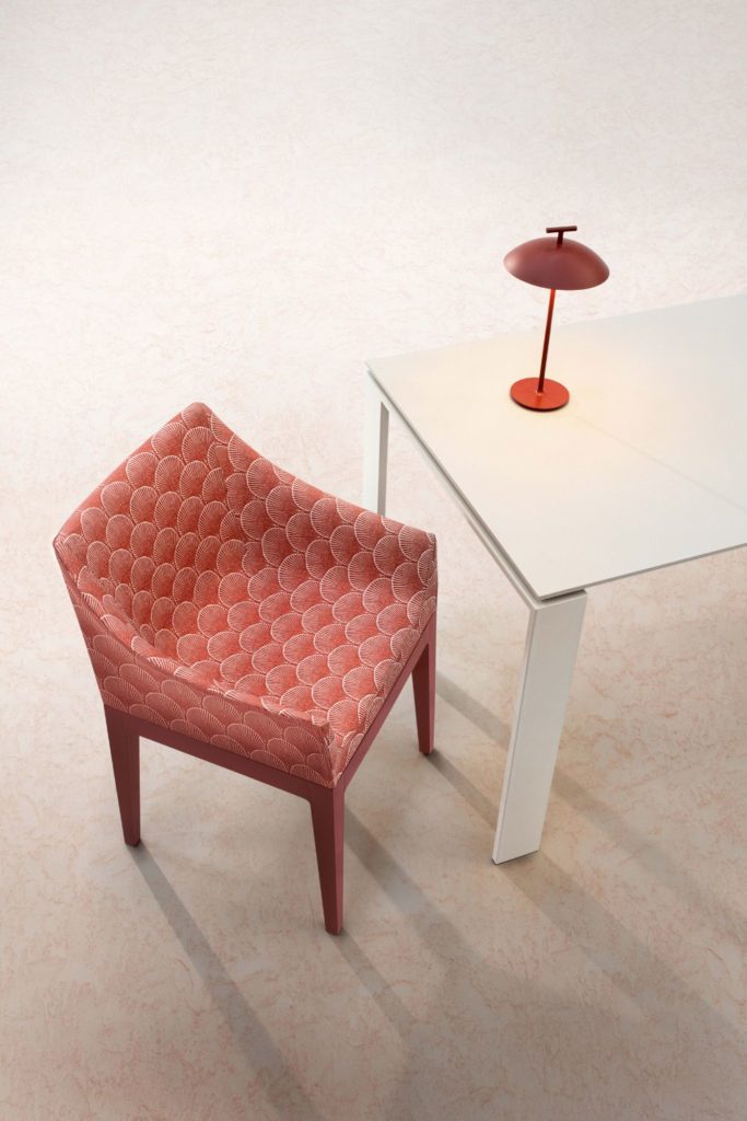 Red modern armchair in red Liberry print, with a white table and a wireless red lamp beside