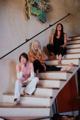 Three women sitting on a white staircase