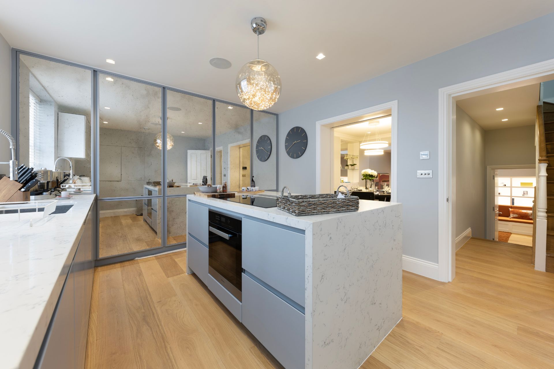 Modern kitchen with white cabinets, a central island, and a mirrored feature wall