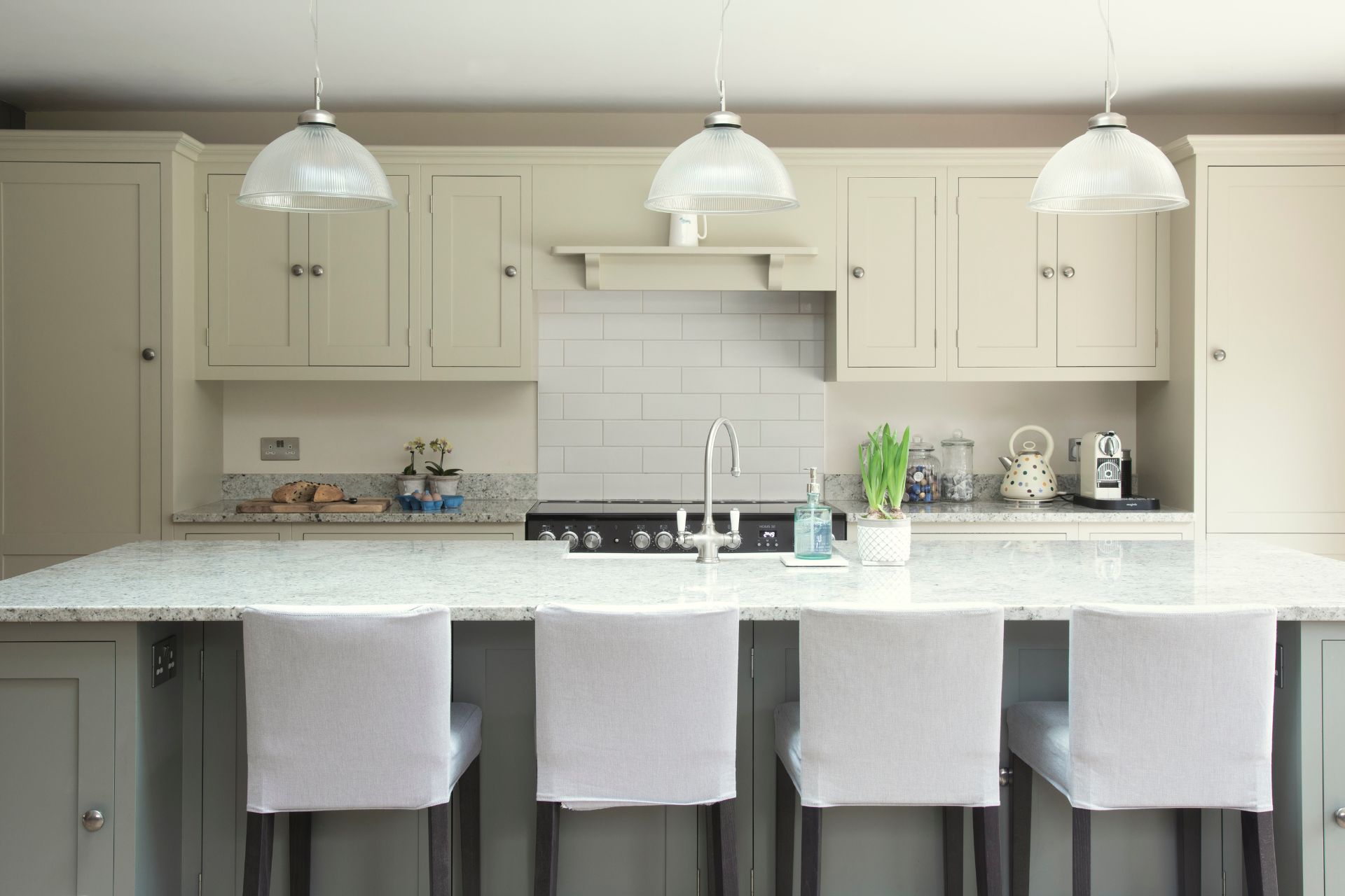 Pale green Shaker kitchen with grey island and white bar stools