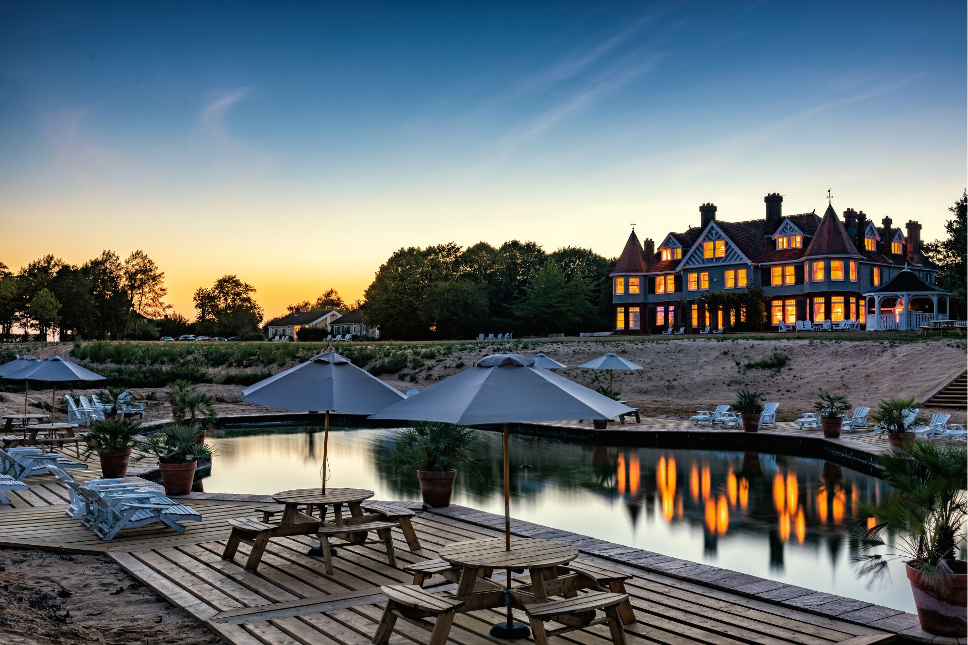 View of large Edwardian home with swimming pool and outdoor seating, shot at dusk