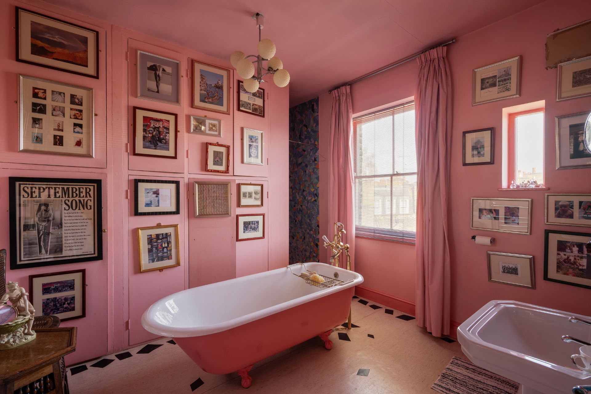 Powder pink bathroom with wooden floors and matching pink bathtub