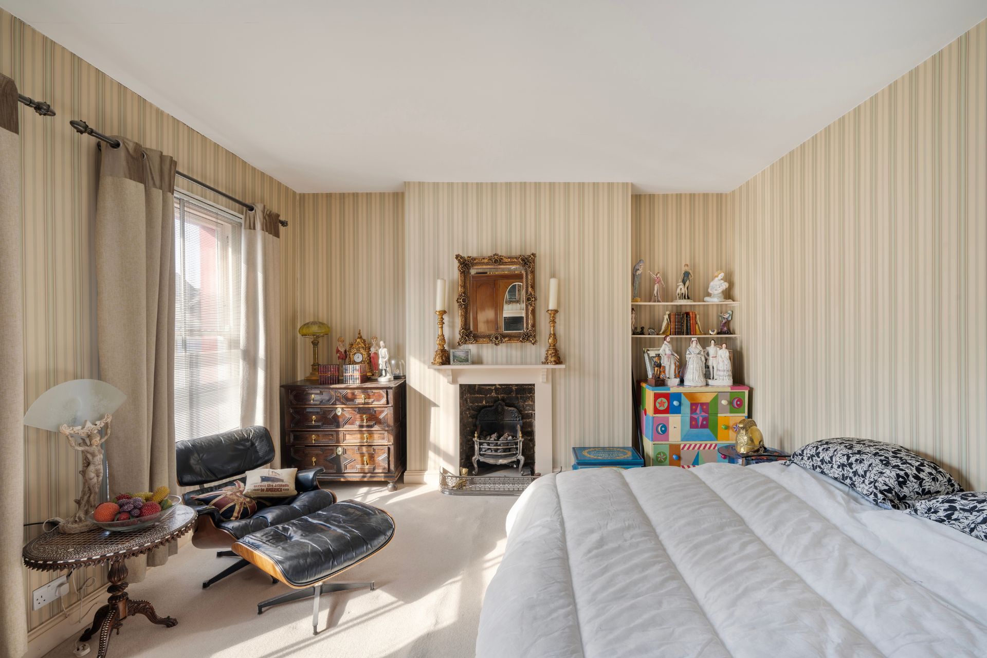 Bedroom with striped cream and white wallpaper and a fireplace