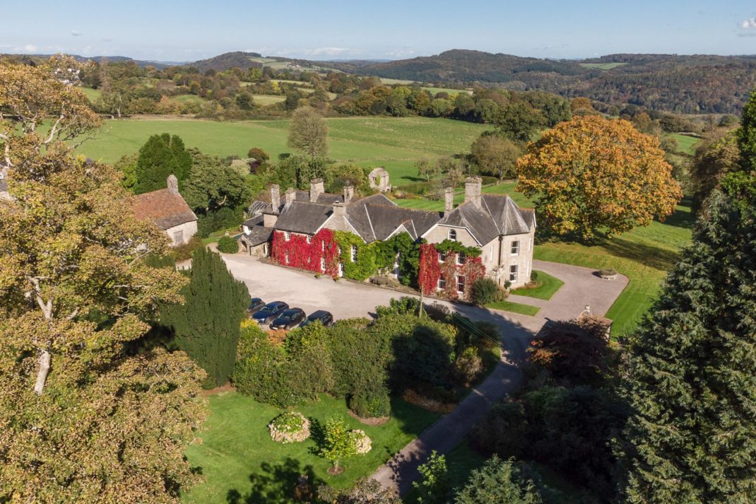 Aerial view of ivy-clad country home with valleys behind