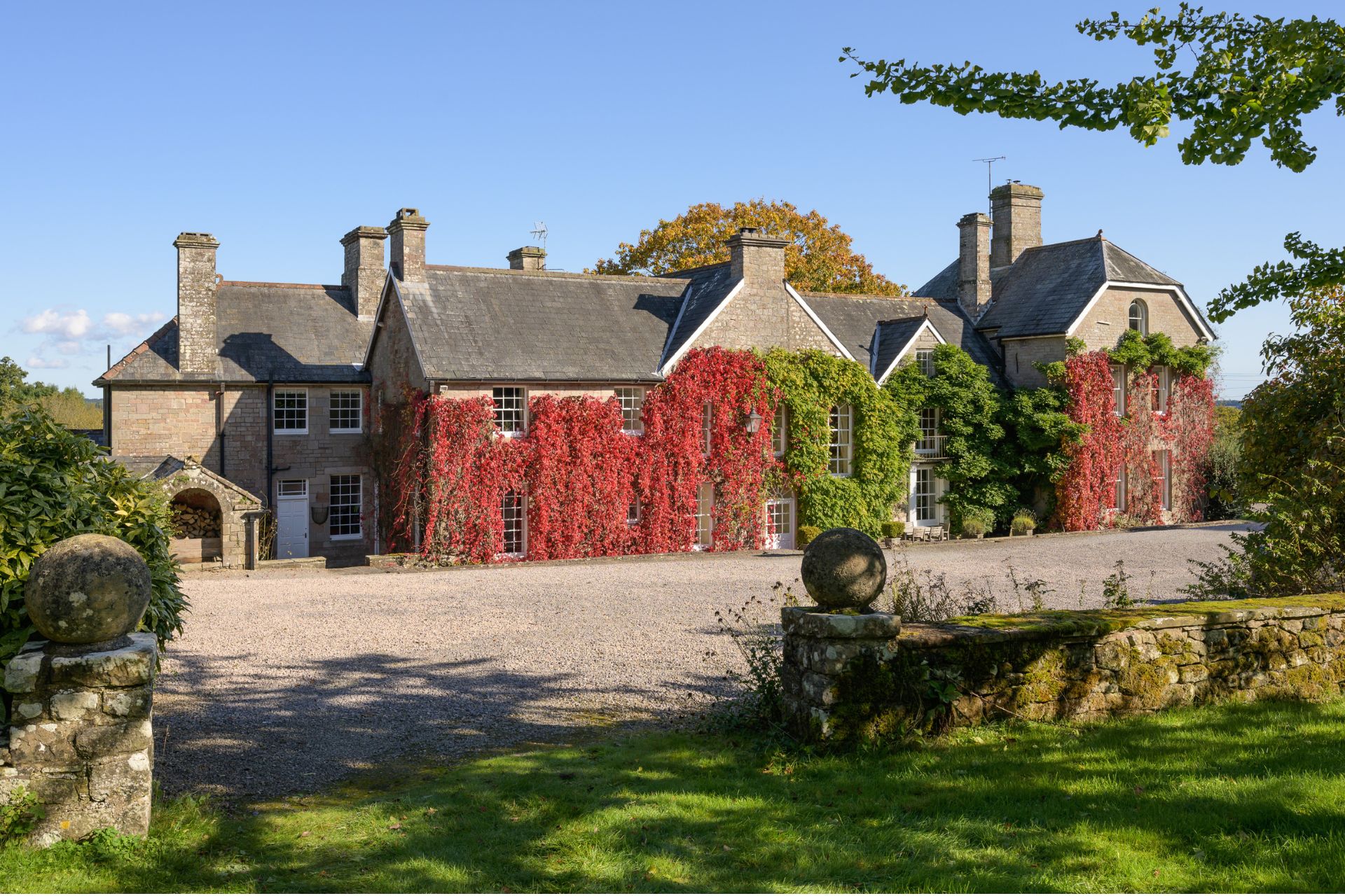 Front view of ivy-clad Welsh country home with gravel driveway