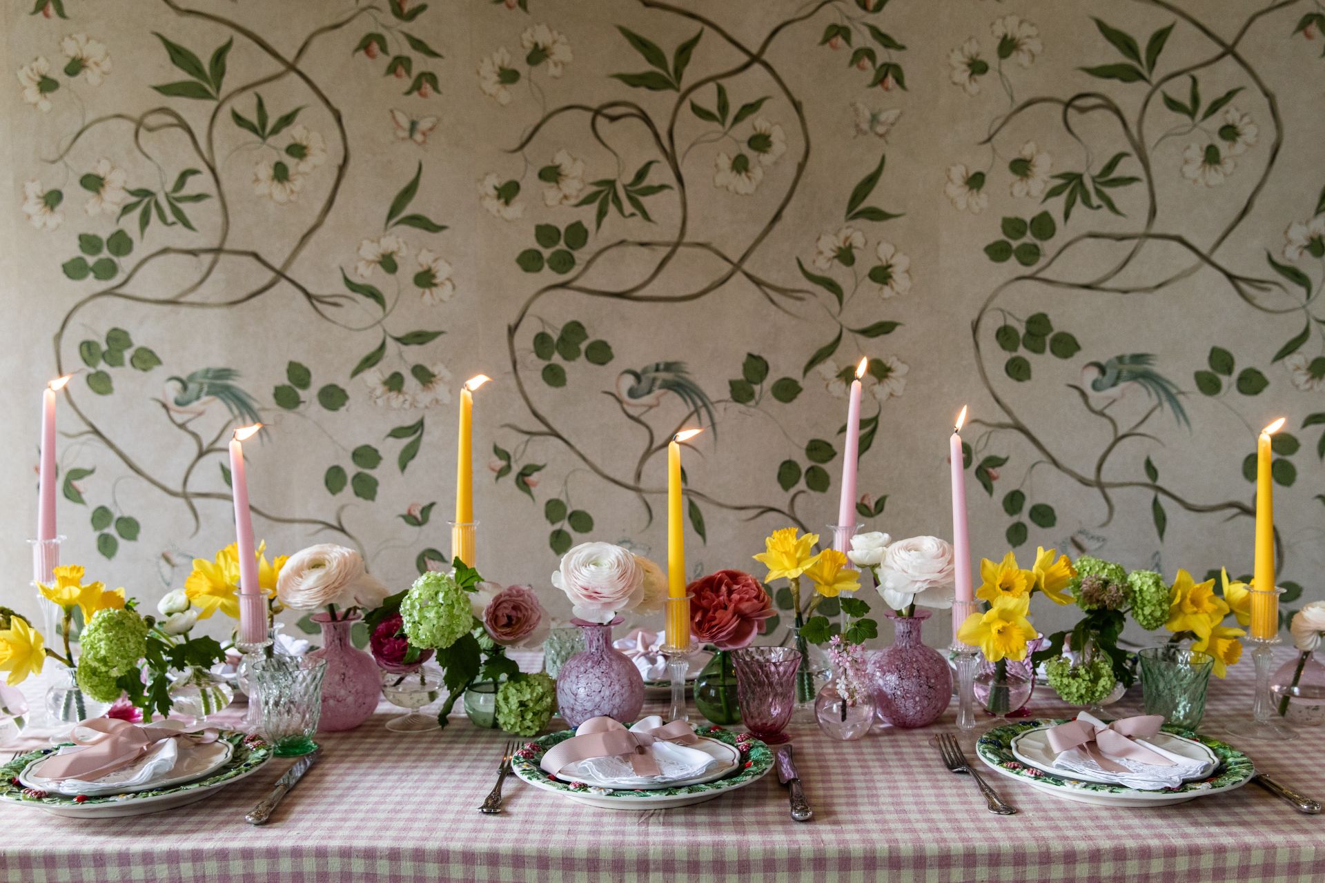 Pastel Easter table with pink napkins, daffodils, and pink and butter yellow tapered candles