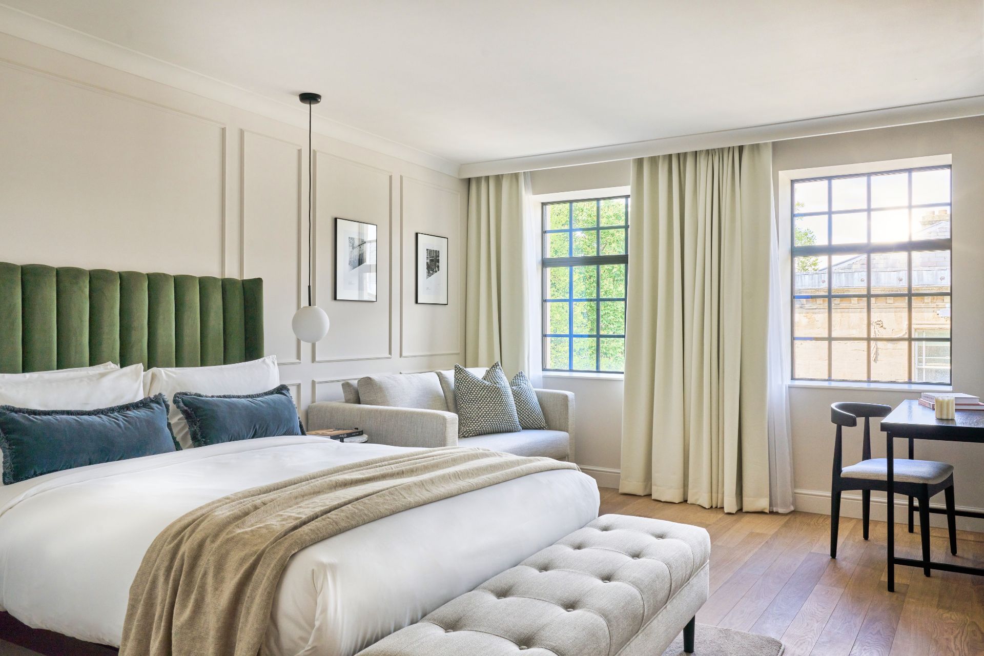 Hotel bedroom with cream curtains, white bedding, and green velvet bedframe