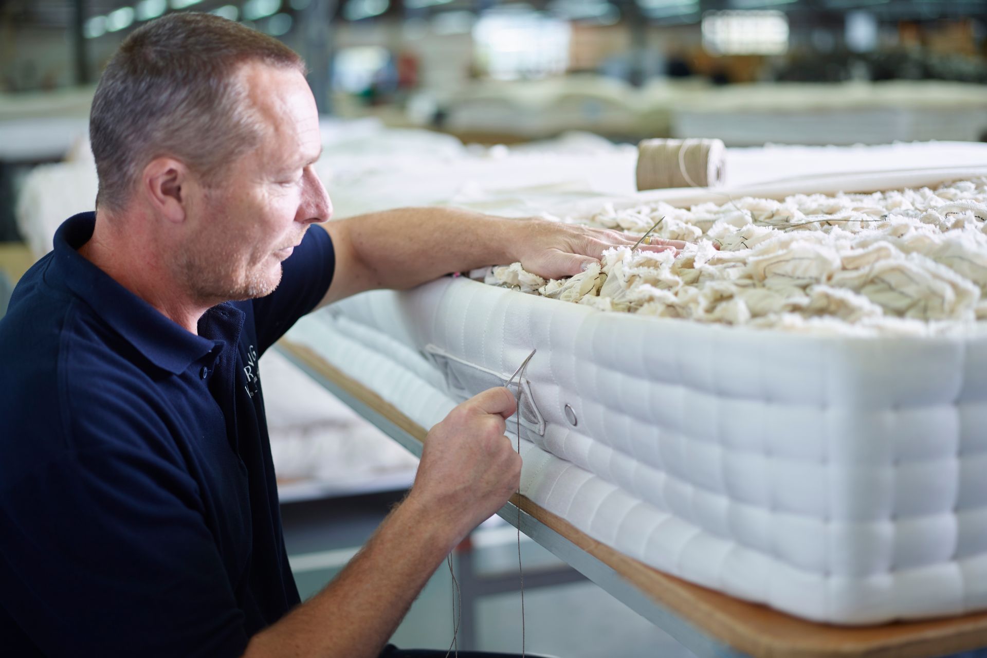 Craftsman side-stitching a luxury mattress using wool