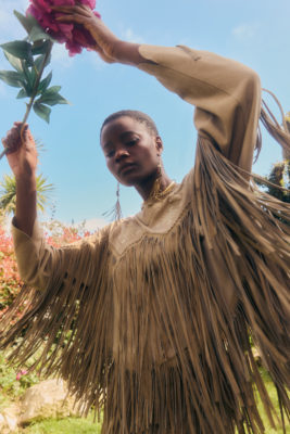 Woman wearing fringe jacket, holding flower