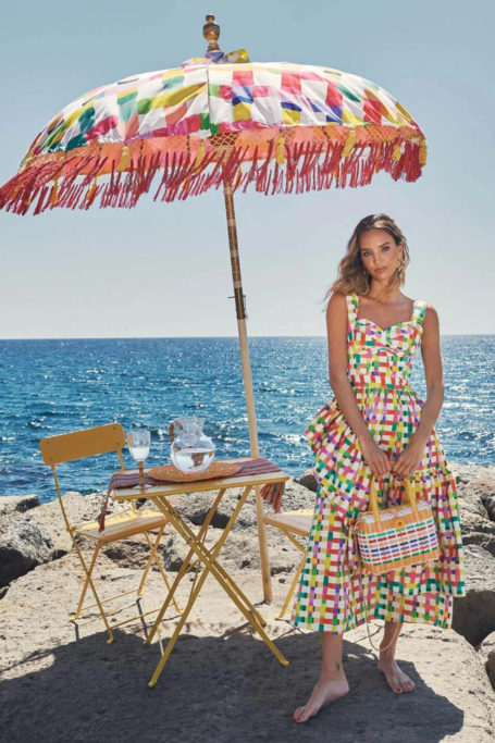 Woman in summer dress stood next to parasol