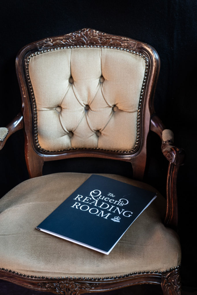A chair with a book reading Queen’s Reading Room