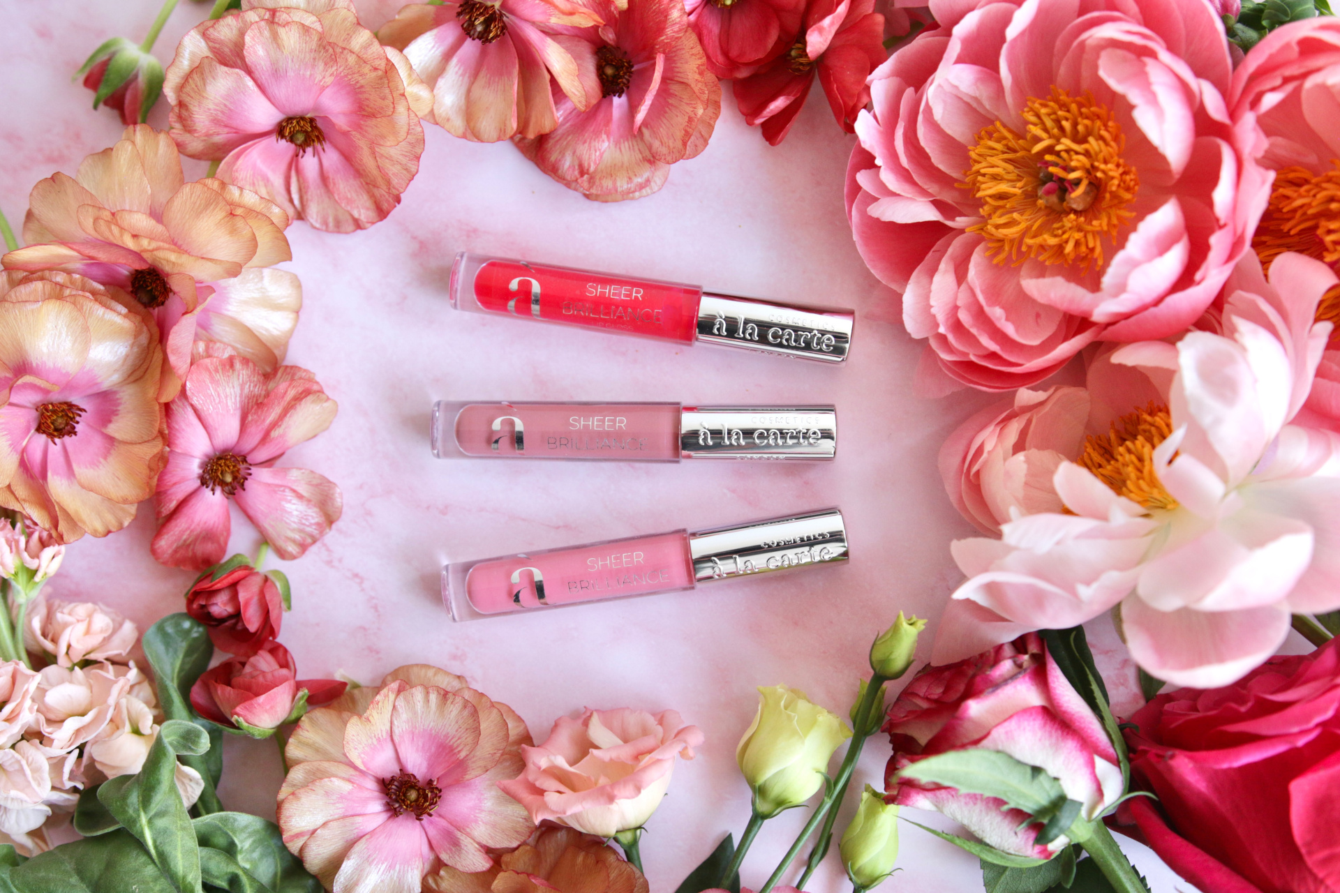 Lip glosses surrounded by flowers