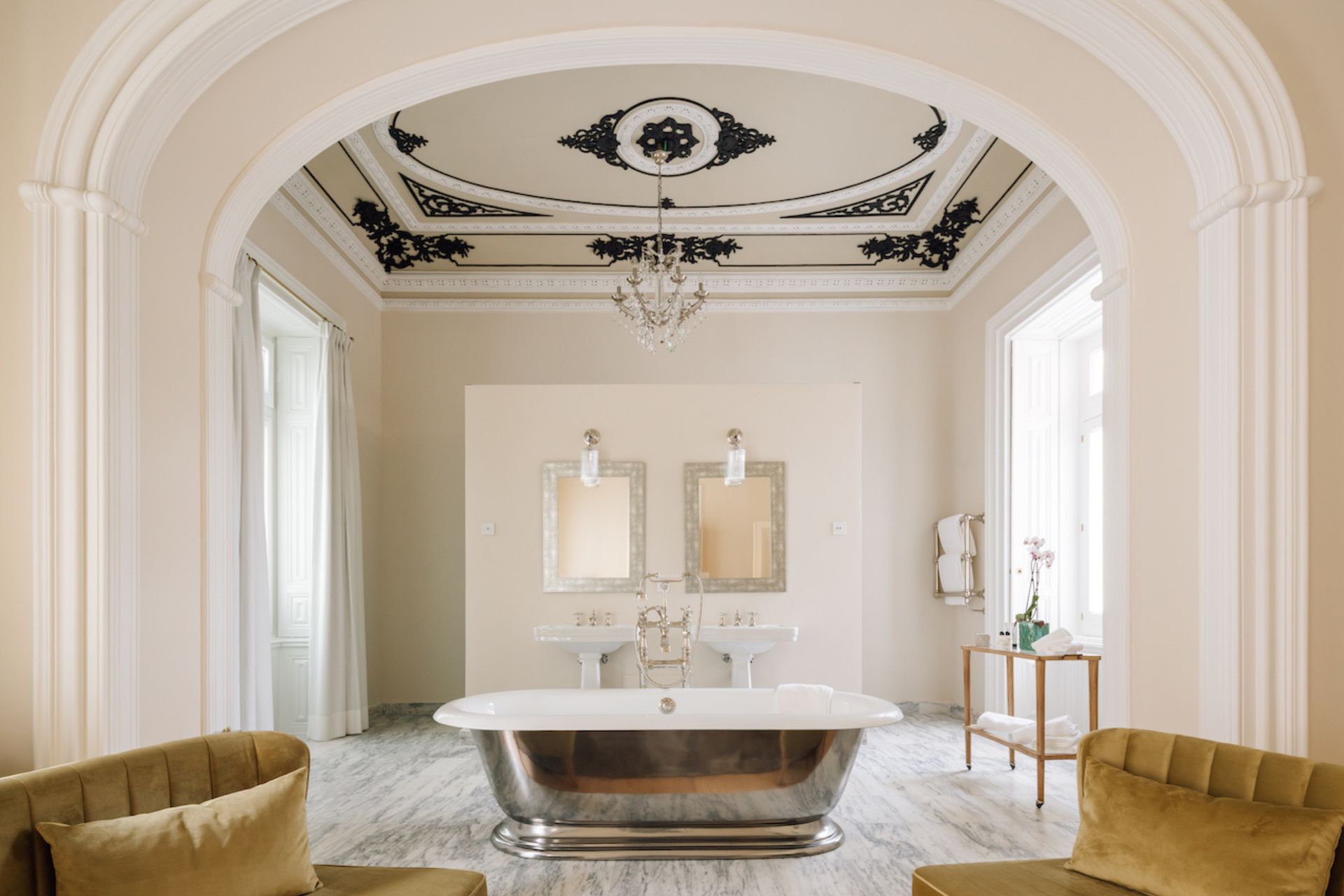 Bathroom with arched doorway and gold freestanding bathtub